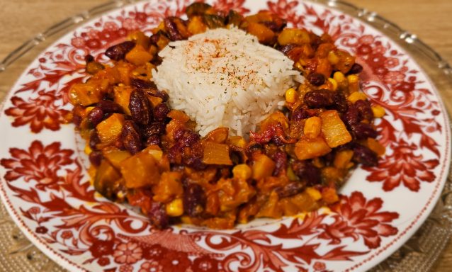 Plat coloré de légumes cuisinés avec du riz sur une assiette décorée.